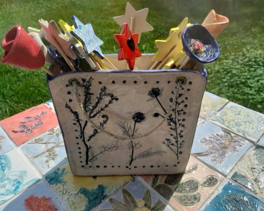 vaso in ceramica con impressioni di fiori e foglie veri su tavolino rivestito in azulejos